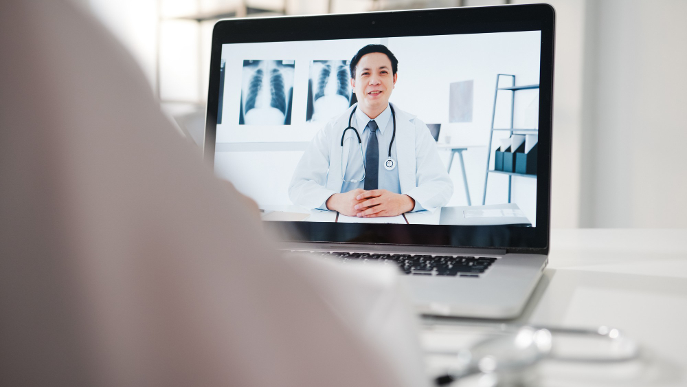 young-asia-male-doctor-in-white-medical-uniform-using-laptop-talking-video-conference-call-with-senior-doctor-at-desk-in-health-clinic-or-hospital